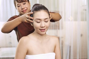 Genç bir kadın baş masajı yaptırıyor.