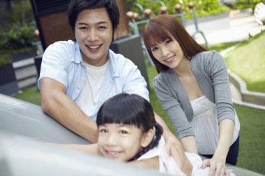 Ebeveynler oyun alanında kızlarıyla oynuyorlar.