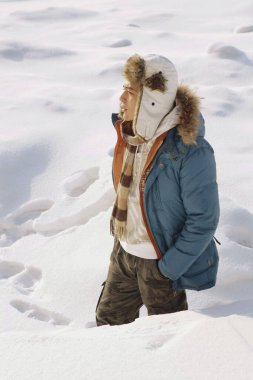 Elleri ceplerinde karda yürüyen bir adam