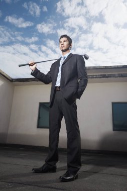 Golf sopası tutan genç bir iş adamı.