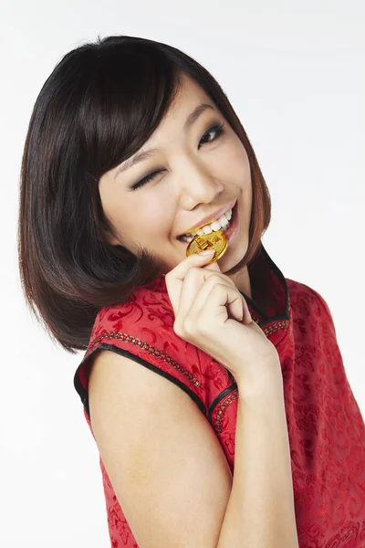 穿着传统服装的女人咬着一枚中国金币 — 图库照片