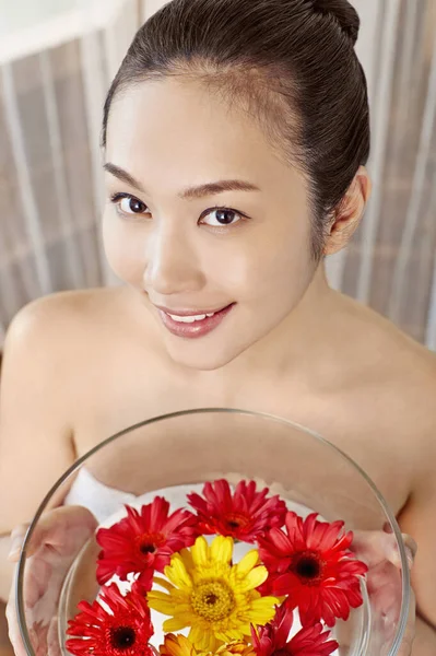 Elinde bir kase çiçek tutan genç bir kadın.