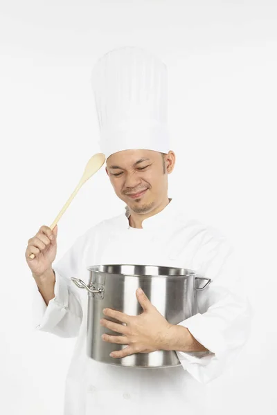 アジア料理人がシチューポットと木製のスプーンを持っていて ストレスを感じます — ストック写真