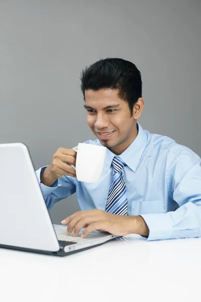 年轻的商人一边在笔记本电脑上工作一边喝着咖啡 — 图库照片