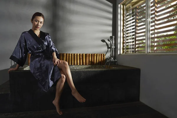 Küvetin kenarında oturan genç bir kadın.