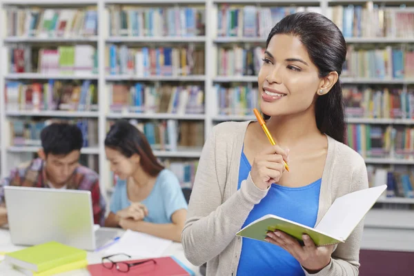 Kütüphanedeki öğrenciler not defteri tutuyorlar.