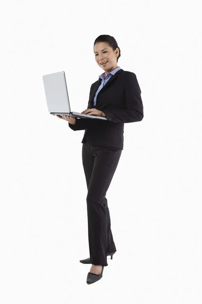 站立时使用笔记本电脑的中年女商人 — 图库照片