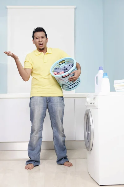 Man with laundry basket looking confused