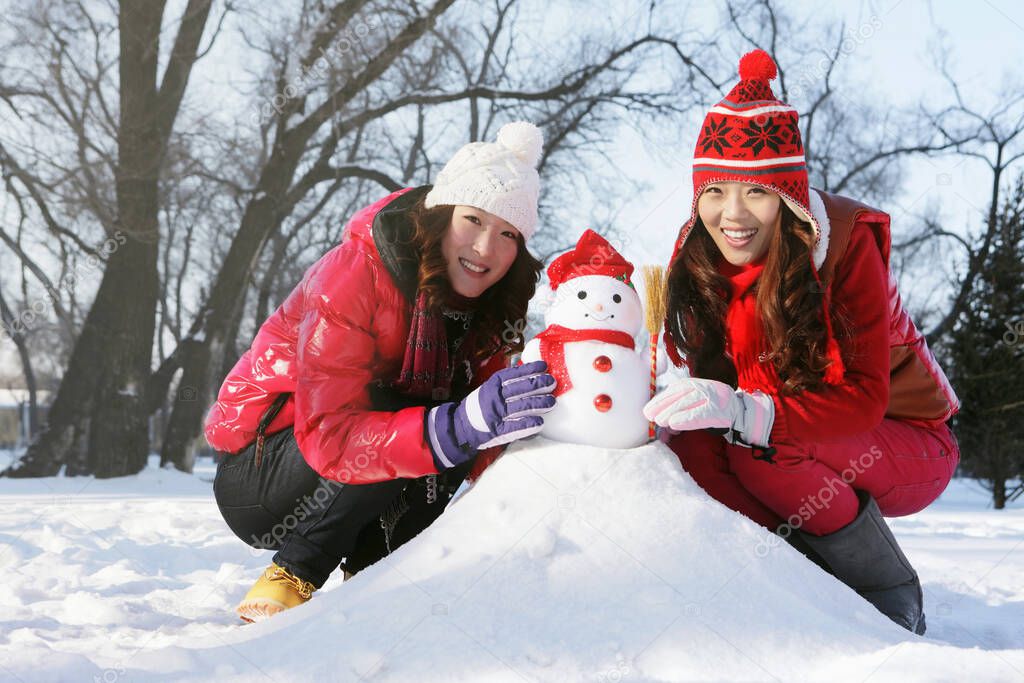 Women building snowman together