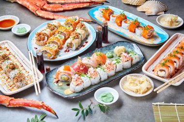 Japon suşisi somon, avokado ve ton balığı, yengeç eti ve Philly peyniri ile birlikte güzel tabaklar üzerinde taze deniz ürünleri arasında restorandaki gri masada..