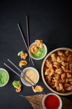 Kızarmış karides ya da siyah zemin üzerinde tahta çubuklarla servis edilen patlamış mısır karidesi, Çin konsepti yiyeceği, üst görünüm, dikey görüntü, kopyalama alanı.