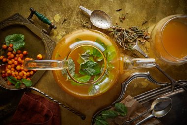 Metal bir masada naneli ve otlu sıcak deniz dikenli çay, kaliteli aksesuarlı, üst görüşlü, iyileştirici çay konsepti, bağışıklık desteği