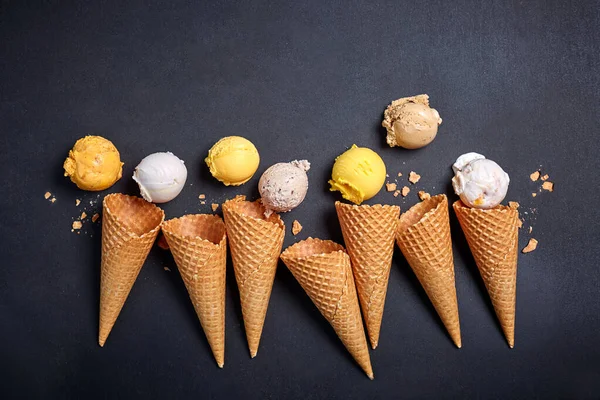ice cream in cones, various types of ice cream in waffle cones on a black background, copy space