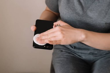 Kadınların elleri virüslerden korunmak ve temizlemek için cep telefonlarına dezenfektan sıkar. Coronavirus konsepti