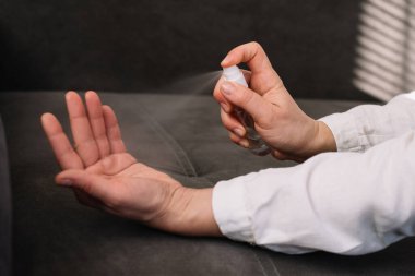 Kadın ellerini alkol bazlı el yıkama spreyiyle temizliyor.