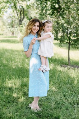 Genç mutlu annenin portresi. Bebeğini kucağında tutuyor ve parkta gülümsüyor. Anneler günün kutlu olsun.!