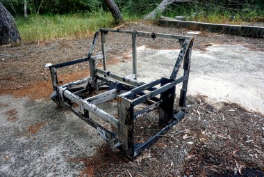 Yeşil ve kahverengi bir tarlanın ortasında terk edilmiş bir bank.