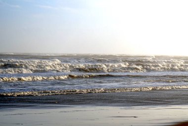 Kışın kumsalda fırtına, mavi gökyüzü ve tehlikeli okyanus
