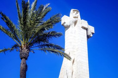 Mavi gökyüzündeki palmiye ağacının yanında bir keşişin beyaz heykeli