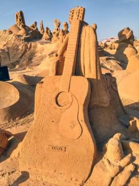 guitar sculpted in sand, a summer day clipart