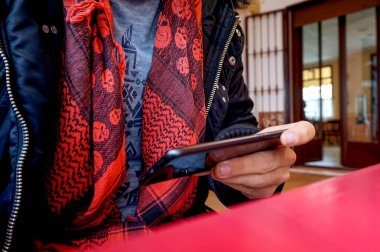 Elinde cep telefonu ve kırmızı atkısı olan bir adam.