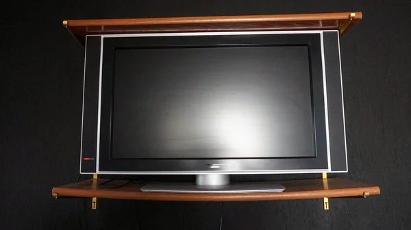 Telewizor Umieszczony Pomiędzy Dwiema Drewnianymi Półkami Czarną Ścianą Tle — Zdjęcie stockowe