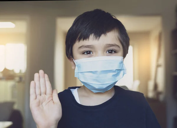 Kid in isolation wearing medical protection face mask show stop gesture with his hand, Child boy feeling bored have to stay at home during corona virus home quarantine, Protective measures against spreading of Covid-19