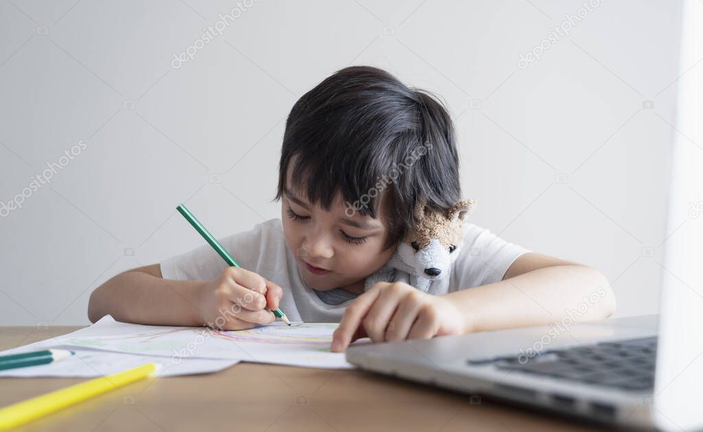 Happy kid having fun watching cartoon on computer, Child using digital pad searching the ideas on internet for his drawing art homework, Home schooling, Social Distancing, E-learning online education