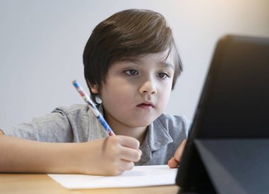 Ödevi için tablet kullanan okul çocuğu kendini izole etme, covid-19 kilitlenme sırasında internette dijital tablet araması yaparak ev ödevi yapan çocuk