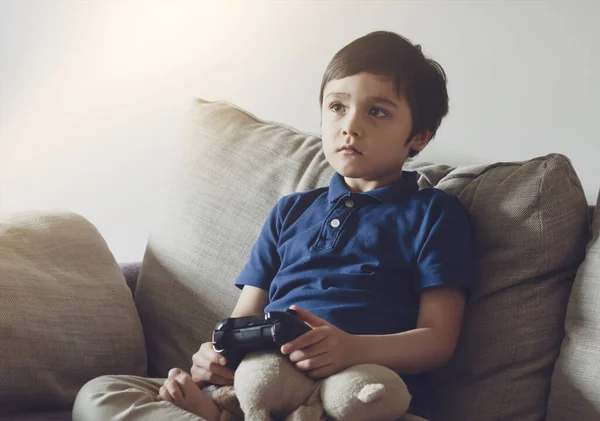 Portrait of kid holding video game or game console.Child playing game online at home while school off, Boy stay at home during covid-19 lock down,Quarantine and Social distancing or self  isolation