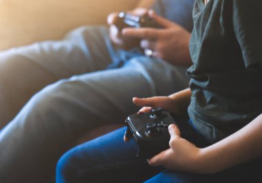 Hands Holding video oyunu veya oyun konsolu. Çocuk çocuk ve baba oyun oynarken okullar kapalı, karantina ve sosyal uzaklık ya da kişisel izolasyon kavramı sürerken evde kalıyorlar.