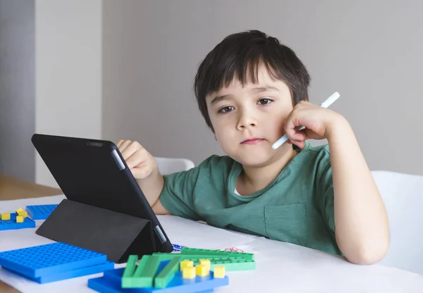 School kid using tablet for homework,Child looking out deep in thought,Boy stay at home learning online lesson from school application,Home school,Distance education,E-learning,Self distancing concept