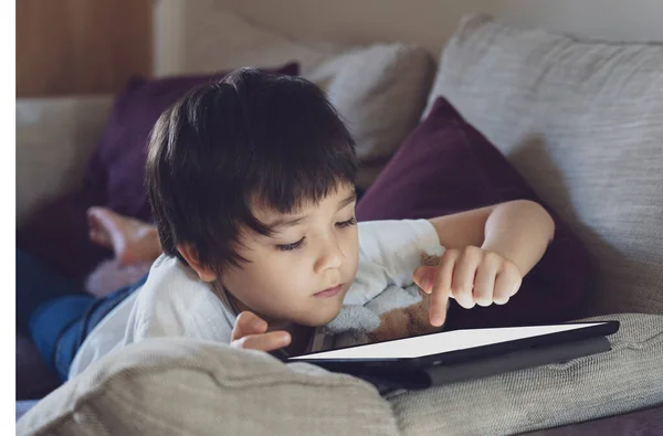 Anak Terisolasi Menggunakan Tablet Untuk Mengerjakan Anak Berbaring Sofa Santai — Stok Foto