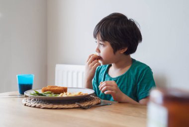 Pazar akşamı evde ev yapımı balık kroket ve patates kızartması yiyen 5 yaşındaki çocuğun portresi öğle yemeği yiyen mutlu bir çocuk sağlıklı ve taze yemek yiyen çocuklar sağlıklı yaşam tarzı konsepti.