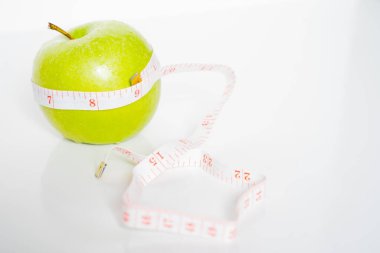 Sağlıklı beslenme ve beslenme şeklini simgelemek için etrafına şerit sarılmış yeşil bir nene elması.