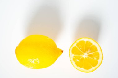 Sade beyaz arka plana karşı tam bir limon ve yarım limon