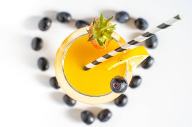 Siyah üzümler, ortada turuncu bir kokteyl ile beyaz bir arka planda aşk kalbi şeklinde serilmiştir.