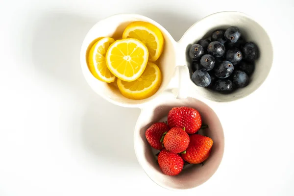 Dilimlenmiş limon, çilek ve siyah üzümlü servis tabağı.