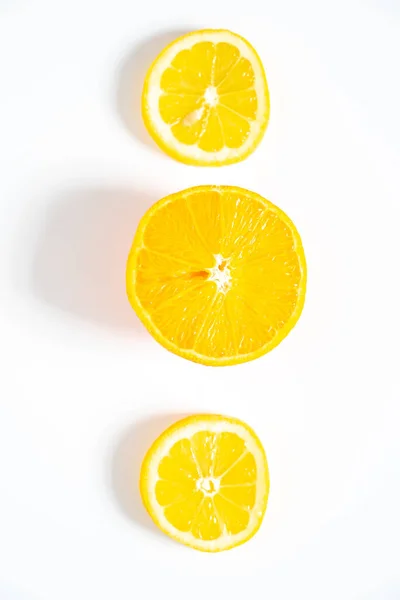 İki dilim limon ve bir dilim portakal sade beyaz arka plana serilmiş.