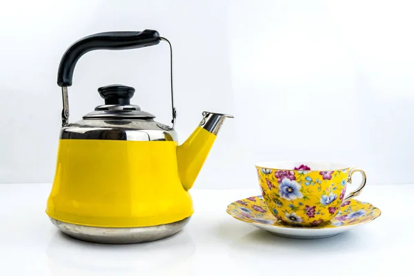 白い光沢のあるテーブルの上に黄色のティーポットとお茶カップ — ストック写真