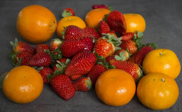 Dużo Świeżych Pomarańczy Truskawek Ciemnoszarym Tle Organiczne Owoce Widok Góry — Zdjęcie stockowe