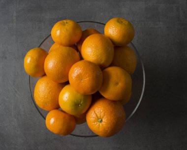 Cam kasede bir sürü portakal var. Yaz meyveleri hala hayattadır. Koyu gri arkaplan. 