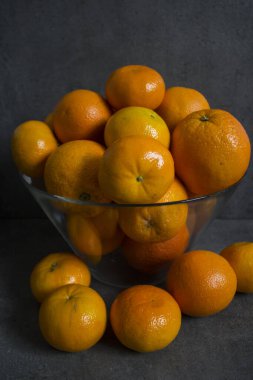 Cam kasede bir sürü portakal var. Yaz meyveleri hala hayattadır. Koyu gri arkaplan. 