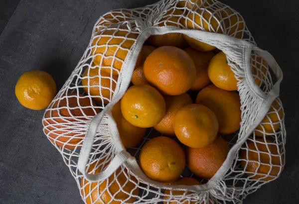A lot of oranges in white cotton mesh bag. No more plastic bags. Ecology concept.