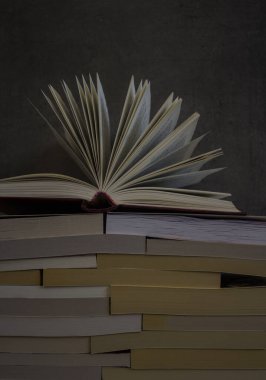 Koyu gri arka planda bir yığın eski kitap. Kitap sayfalarını aç. Kütüphane fotoğrafı. 
