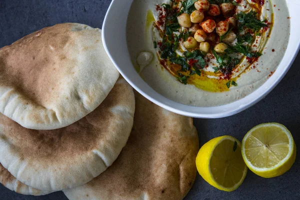 Plate of fresh homemade hummus with pita bread on the table. Authentic food of Middle East. Healthy eating concept. Vegan balanced dish. Traditionalmeal of Israel.