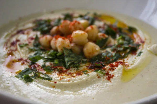 Plate of fresh homemade hummus close up photo with pita bread on the table. Authentic food of Middle East. Healthy eating concept. Vegan balanced dish. Traditional meal of Israel.