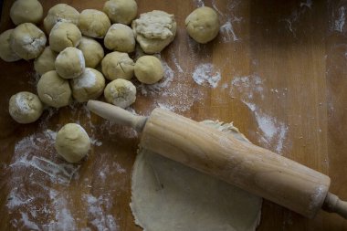 Hamur topları, makarna rulosu, ahşap masada un. İçindekiler fotoğrafı kapatır. Ev yapımı ekmek.. 
