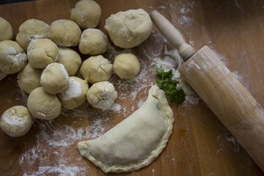 Kutub, otantik Azerbaycan yemeği. Canlı yemek fotoğrafı. İçindekiler üst görünüm. Mutfak masasında hamur topları. Geleneksel yemek yapıyorum. Taze bitkiler ve peynir.. 
