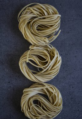 Koyu gri arka planda Tagliatelle makarnası. Üst görünüm yakın çekim fotoğrafı.  